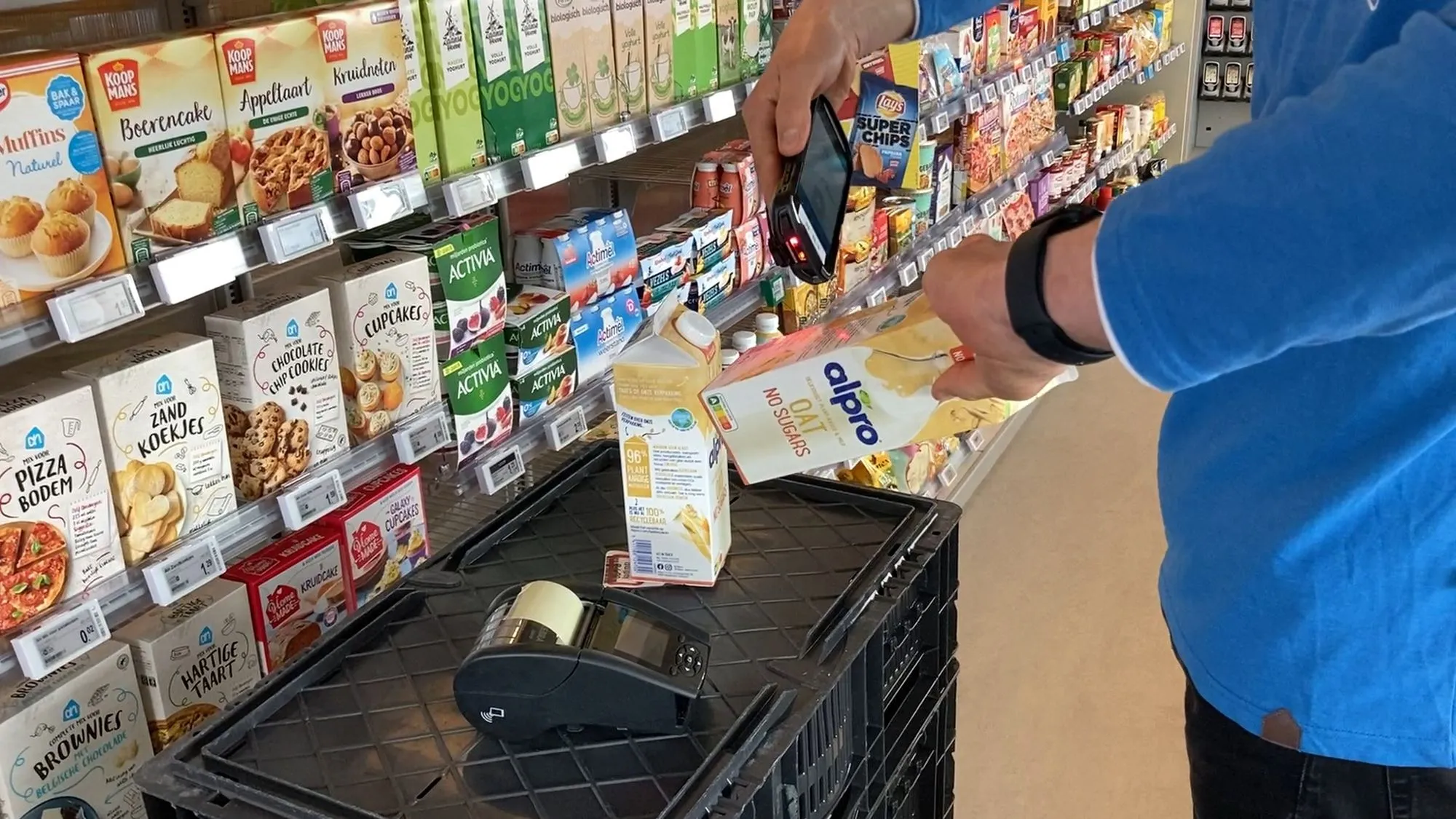 An employee scans a carton of oat drink with a hand terminal above a crate with a portable sticker printer